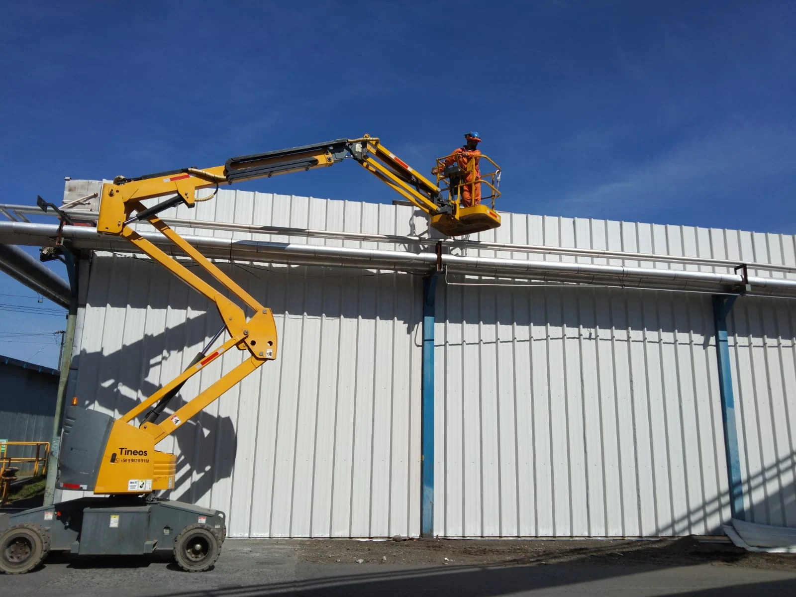 Instalación de revestimientos en una nave industrial con plataforma elevadora